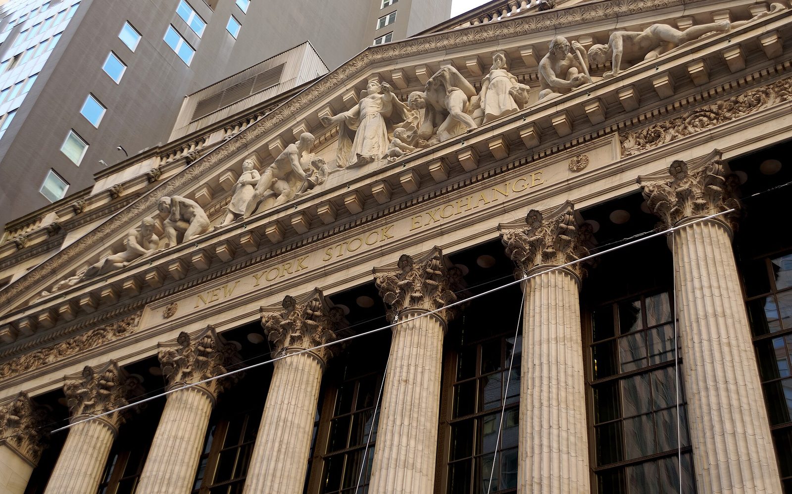 The columned Broad Street facade of the New York Stock Exchange, draped with an American flag.