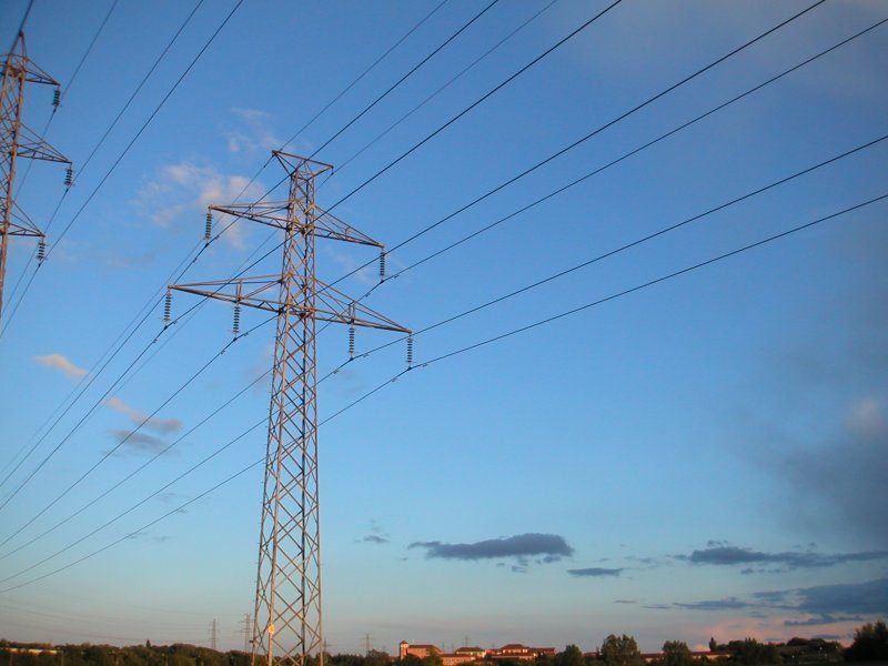High-voltage electricity transmission lines against the sky.