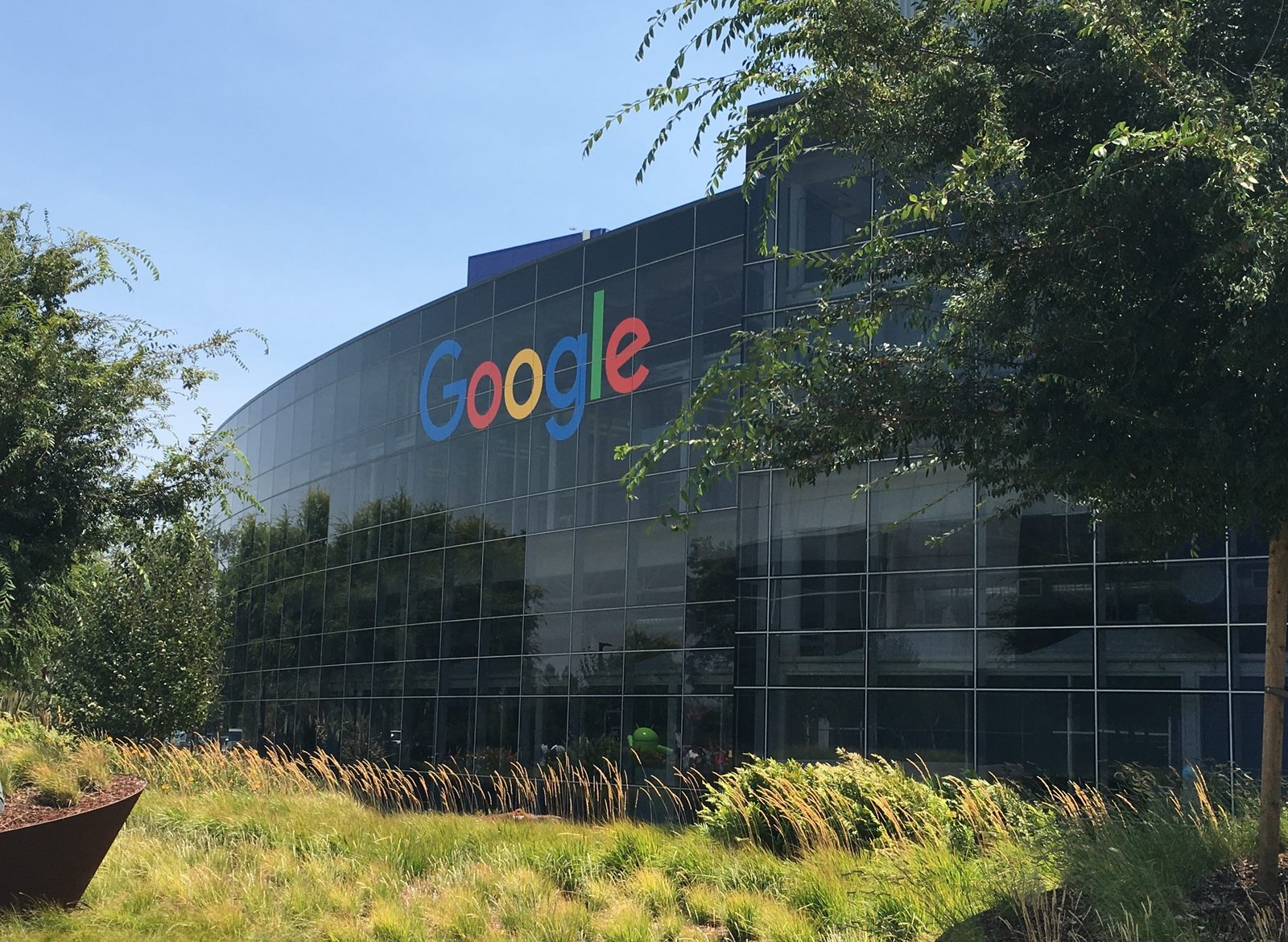 The Googleplex headquarters in Mountain View, California, with the Google logo on a low glass building.