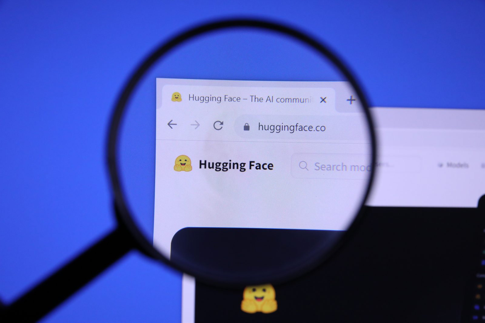 The Hugging Face website logo viewed through a magnifying glass.