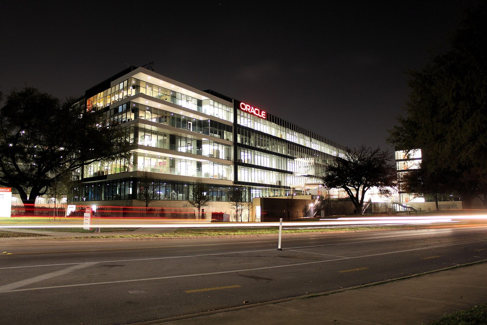 Oracle's Austin campus at night, the company logo lit above traffic light trails.